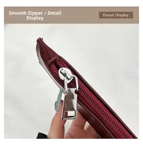 Macro shot of smooth metal zipper and silver hardware on wine red leather bucket bag