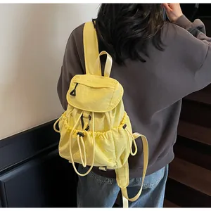 Rear view of a model wearing a bright yellow nylon drawstring backpack on a staircase