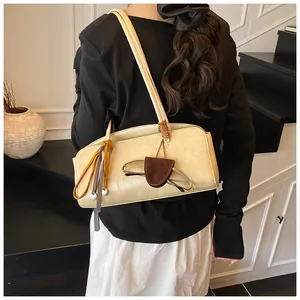 Détail d'un sac bandoulière crème avec glands rétro et breloque en forme de cœur