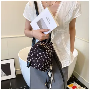 Detailed shot of a black mini backpack with white bow patterns worn by a model