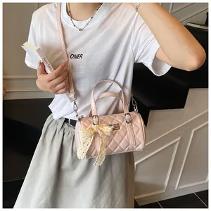 Détail du sac barillet matelassé rose clair avec nœud en dentelle et finition PU brillant