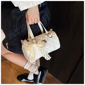 Détail de sac polochon blanc matelassé avec nœud en dentelle et boucles argent