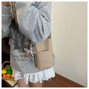 Close-up of textured faux leather phone bag in light brown with silver star charm