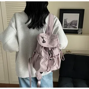Detail view of pink nylon drawstring backpack on model showing buckle and texture