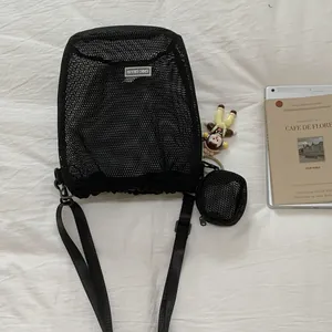 Detailansicht schwarze Umhängetasche aus Mesh mit Logo, Mini-Beutel und kleinem Anhänger