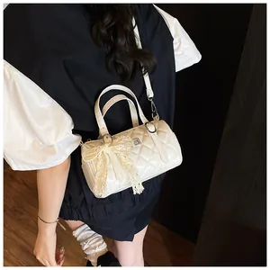 Détail du sac cylindrique matelassé blanc avec un nœud en dentelle et bandoulière