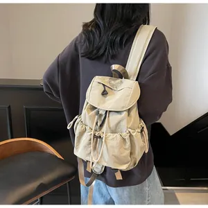 Detail of lightweight khaki canvas backpack with drawstring pockets and flap closure