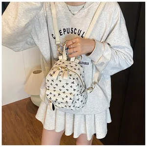 Close-up of mini backpack with black bow print and gold zippers on a female model