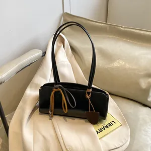 Sac baguette rétro noir minimaliste avec rubans colorés sur un blazer beige chic