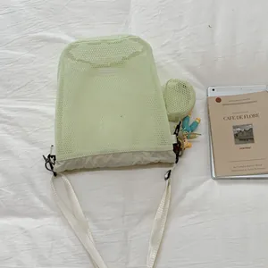 Detail einer hellgrünen Mesh-Umhängetasche mit Kordelzug und kleiner runder Tasche