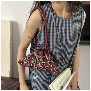 Detail of dark red punk bucket bag with silver metal eyelets and pearl chain strap