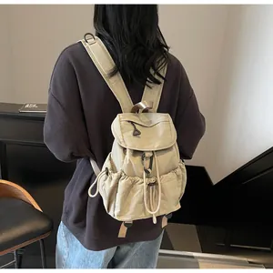 Detail of minimalist beige canvas drawstring backpack with functional black buckle and side pocket