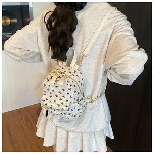 Detail of white mini backpack with quilted texture and bow pattern worn by a model