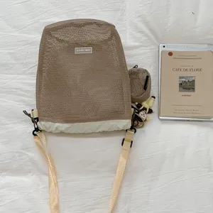 Detailansicht einer zweifarbigen Netztasche mit Kordelzug und süßen Plüschanhängern