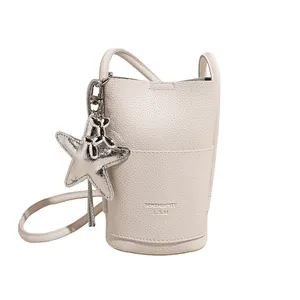 White lychee leather bucket bag with silver starfish and balloon dog charms