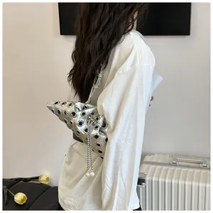 Silver punk bucket bag with metal eyelets and pearl chain detail shown on model