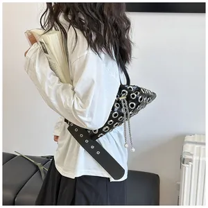 Detail of a black punk-style bucket bag with silver metal eyelets and chain on a model