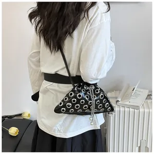 Detail of a punk style rivet bucket bag featuring silver grommets and pearl chain strap
