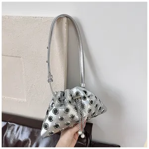 Close-up of metallic silver bucket bag with hollow eyelets and pearl chain detail