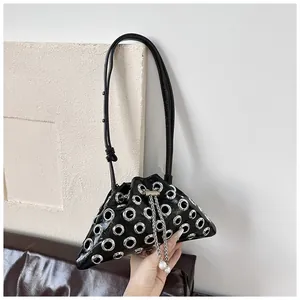 Detail of black punk bucket bag with silver eyelets, chain drawstring and pearl charms
