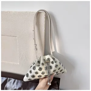 Macro view of cream bucket bag showing silver eyelets and chain fringe with pearl details