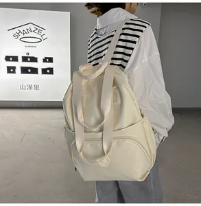 Minimalist beige water-resistant backpack with multiple compartments and side pockets shown in use