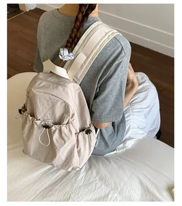 Detail view of the beige nylon backpack with drawstring pocket on a female model