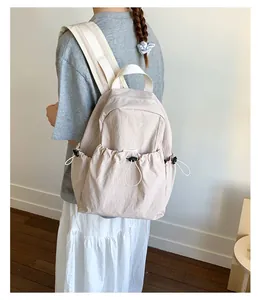 Detailed side view of beige pleated backpack with drawstring pockets on female model
