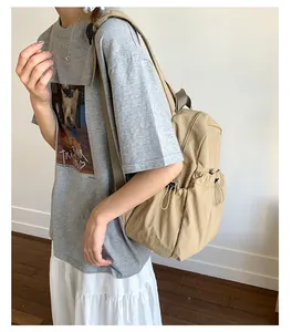 Khaki canvas backpack detail with side drawstring closure and buckle worn by model