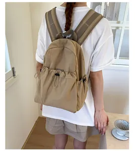 Detail of khaki pleated backpack with wide padded straps and adjustable drawstring side pockets