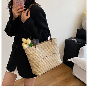 Large straw tote bag with brown handles and black printed text for beach holidays