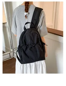 Rear view of minimalist black backpack with drawstring pocket worn on person in clean interior