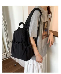 Detail of a minimalist black nylon backpack featuring functional side drawstring pockets