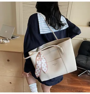Detail of off-white lychee leather tote bag with a pink polka dot scarf on handle