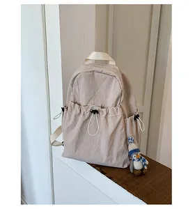 Close-up of beige nylon backpack with drawstring pockets and minimalist design