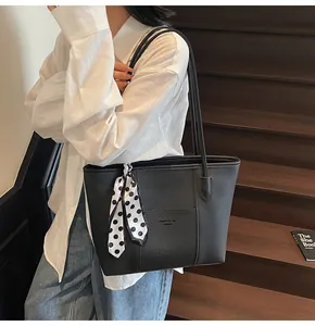 Detail of black pebbled leather tote bag with polka dot scarf on stairs