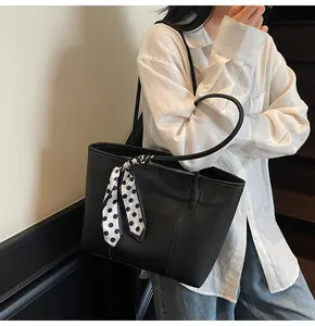 Detailed view of black lychee grain tote bag with a polka dot scarf on a model's shoulder