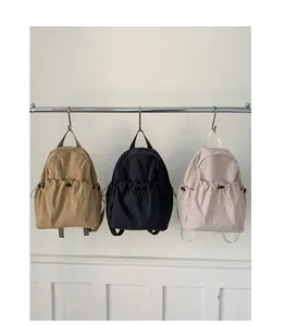Detailed view of lightweight nylon backpacks in khaki, black, and light pink with drawstrings