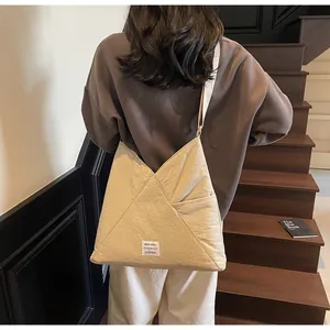Close-up of beige canvas tote bag showing geometric stitching and side pocket detail