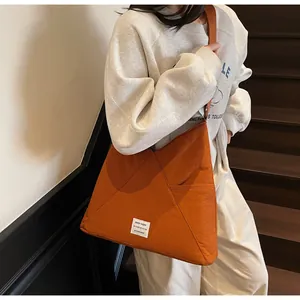 Detail of the orange triangle tote bag showing geometric stitching and white woven label