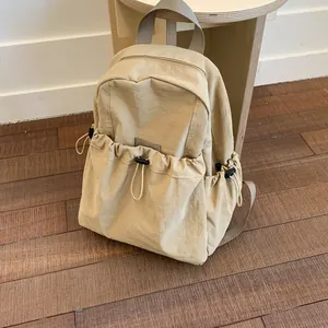 Minimalist beige campus backpack with large drawstring front pocket and grey top handle