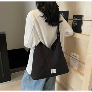 Detail of minimalist black canvas tote bag with lettered patch and adjustable strap