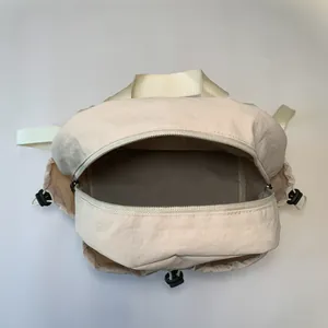 Cream colored pleated nylon backpack with metallic zipper and wide ribbon handle details