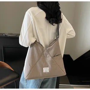 Close-up of slouchy taupe nylon tote bag with geometric stitching on a model shoulder