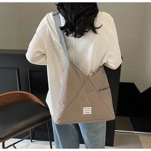 Detail view of large grey triangular canvas tote bag with adjustable shoulder strap