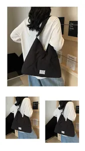 Detail of black triangular canvas tote bag with white square label and wide strap