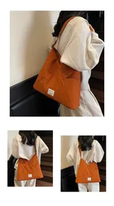 Detail view of large orange nylon tote bag with decorative black and white woven label