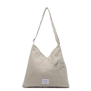 Minimalist beige canvas triangle tote bag with adjustable strap and side pockets