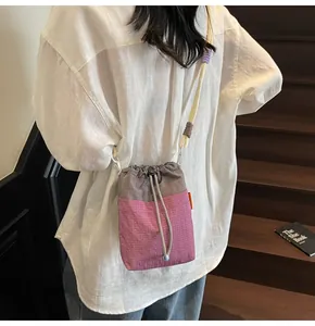Detail of trendy bucket bag showing contrast stitching, drawstring closure and rope strap