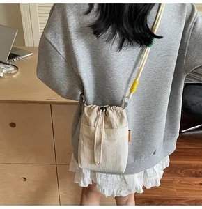 Detail of beige drawstring crossbody bag featuring a colorful knotted rope shoulder strap
